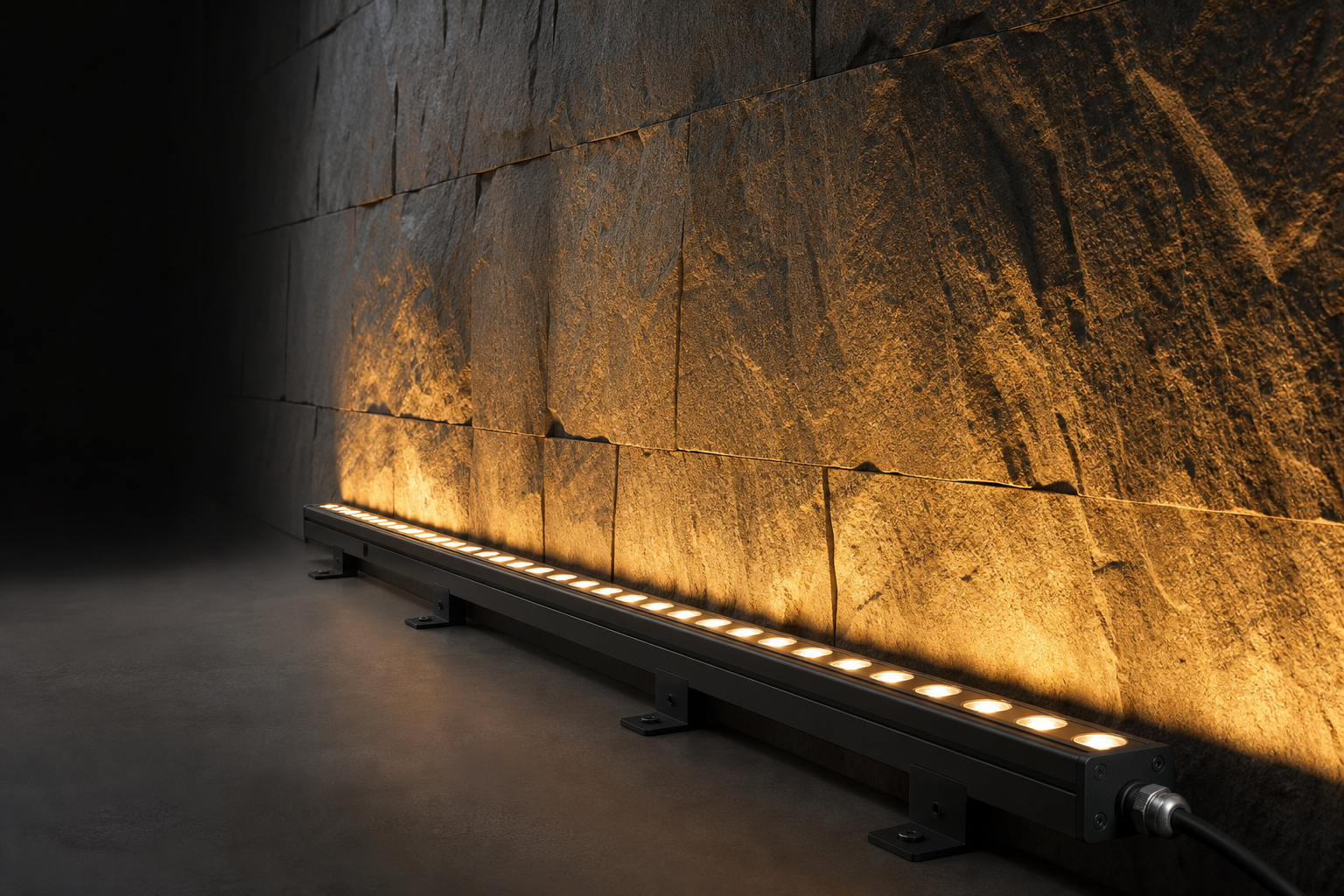 LED wall washer light grazing a textured stone wall with amber light at night